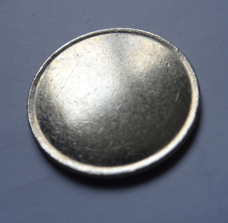 Photo showing a modern coin blank ready to be struck, otherwise known as a planchet or flans.